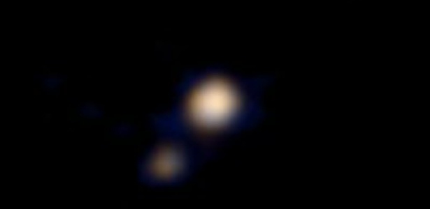  A Nasa (Agência Espacial Americana) publicou nesta quarta-feira (15) a primeira imagem em cores de Plutão e sua lua maior, Caronte, obtida pela sonda New Horizons, que deve chegar ao planeta anão no mês de julho - NASA