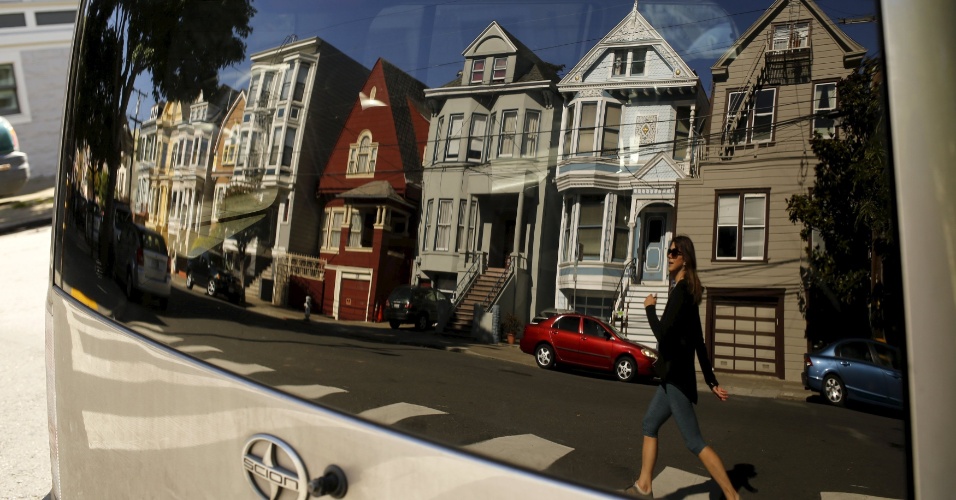 17.abr.2015 - Uma fileira de casas vitorianas e uma mulher são refletidas no vidro de um veículo no bairro de Haight Ashbury, em San Francisco, na Califórnia (EUA)