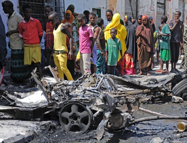 Moradores de Mogadíscio observam o que sobrou de carro-bomba que explodiu perto de um restaurante, em abril - Mohamed Abdiwahab/AFP