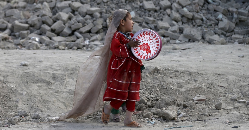 27.abr.2015 - Uma menina brinca com um pandeiro próximo a casa onde mora em Cabul, no Afeganistão