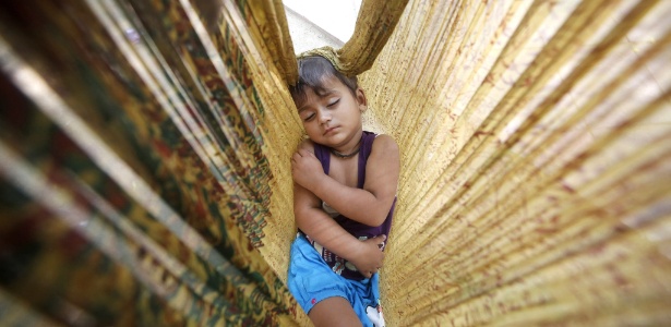 Uma criança dorme em rede em uma estrada em Nova Déli, na Índia - Rajat Gupta/EFE