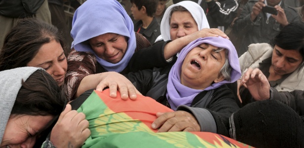 A mãe de um lutador yazidi, morto durante combate com militantes do Estado Islâmico, chora com parentes sobre o corpo de seu filho durante uma cerimônia fúnebre em um cemitério em Sinjar, no noroeste do Iraque - Asmaa Waguih/Reuters