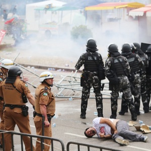 Manifestante caído é observado por policiais militares em Curitiba - Daniel Castellano/AGP/Folhapress