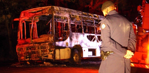 Policial observa ônibus destruído após ter sido incendiado na estrada da Água Espraiada - Nivaldo Lima/Futura Press/Estadão Conteúdo