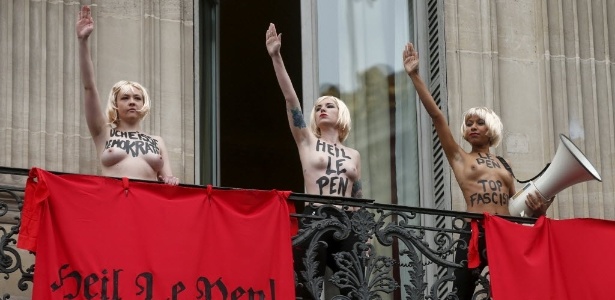 1.mai.2015 - Ativistas do grupo Femen protestaram nesta sexta-feira (1º), em Paris, contra a líder do partido francês de ultradireita Frente Nacional, Marine Le Pen. Com faixas com a frase "Heil Le Pen" em alusão à saudação nazista a Hitler e frases contra a Frente Nacional, o trio atrapalhou o discurso de Marine até ser retirado pela polícia - Benoit Tessier/Reuters