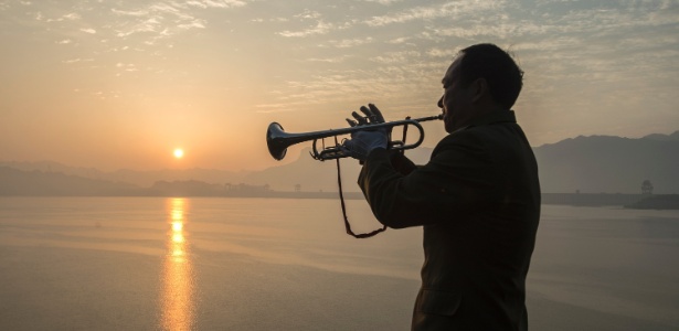 Homem toca trompete à margem do rio Yangtze, em Zigui County, no centro da província de Hubei - Zheng Jiayu/Xinhua