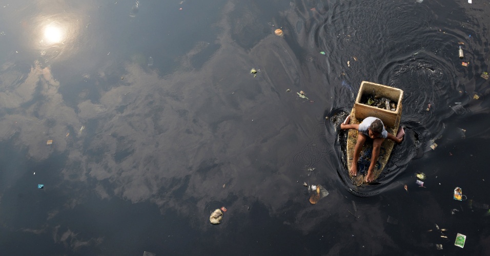 6.mai.2015 - Mulher recolhe lixo reciclável de rio poluído da cidade Navotas, nas Filipinas, com barco improvisado