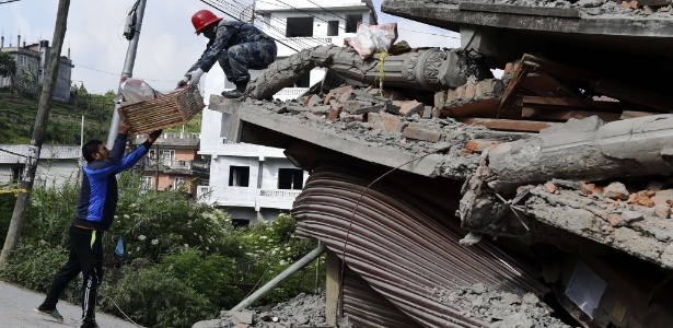 Funcionário da equipe de resgate do Nepal entrega caixa com objetos pessoais a morador de prédio destruído pelos fortes terremotos que atingiram o país - Roberto Schmidt/AFP