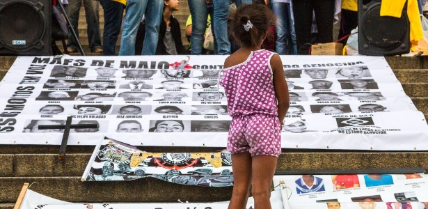Criança observa cartaz com fotos de jovens vítimas de violência na periferia de São Paulo - Dário Oliveira - 15.mai.2015/Código 19/Estadão Conteúdo