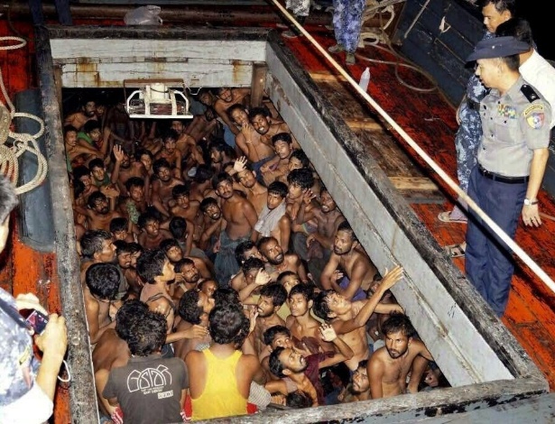 22.mai.2015 - Em foto divulgada pelas autoridades de Mianmar, policiais observam um grupo de imigrantes em um navio em Rakhine