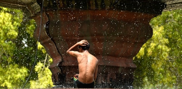  Menino toma banho em fonte em Nova Déli, na Índia. A onda de calor que afeta o país, com temperaturas próximas dos 50ºC em várias cidades, provocou a morte de mais de 800 pessoas, anunciaram as autoridades - Chandan Khann/AFP 