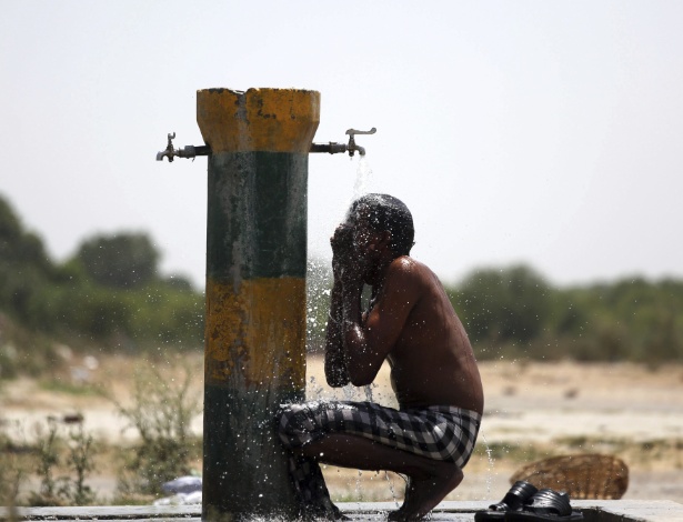 26.mai.2015 - Trabalhador indiano se refresca em bica em Amritsar, na Índia - Raminder Pal Singh/Efe