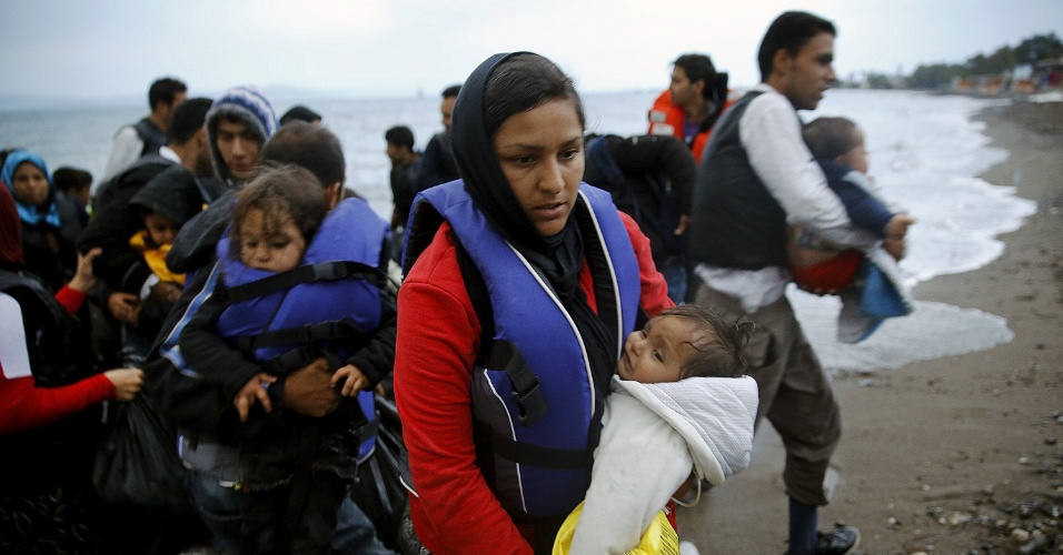 27.mai.2015 - Imigrante afegã carrega bebê ao chegar a uma praia na ilha grega de Kos, nesta quarta-feira (27), depois de atravessar uma parte do mar Egeu, entre a Turquia e a Grécia. A União Europeia (UE) pretende deslocar, nos próximos dois anos, 40 mil refugiados para aliviar a Itália e a Grécia, segundo proposta apresentada em Bruxelas nesta quarta-feira (27)