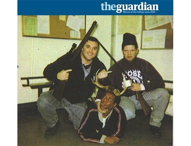 Foto divulgada pela Justiça norte-americana mostra dois policiais segurando armas enquanto um preso é mantido no chão, com chifres, como se tivesse sido caçado - Reprodução/Guardian