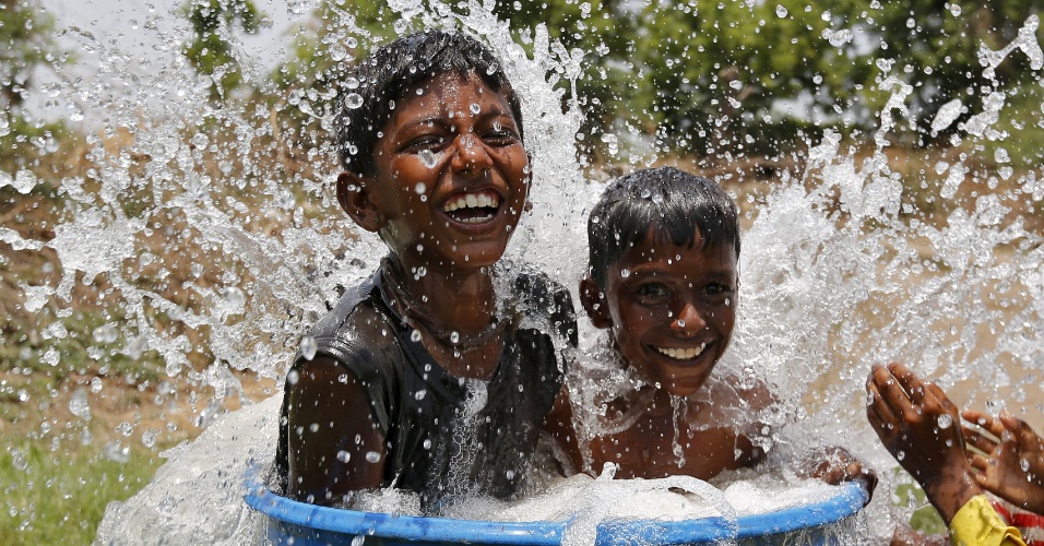 28.mai.2015 - Meninos brincam em uma tina de plástico cheia de água para tentar se refrescar em dia quente de verão, nos arredores de Ahmedabad, na Índia