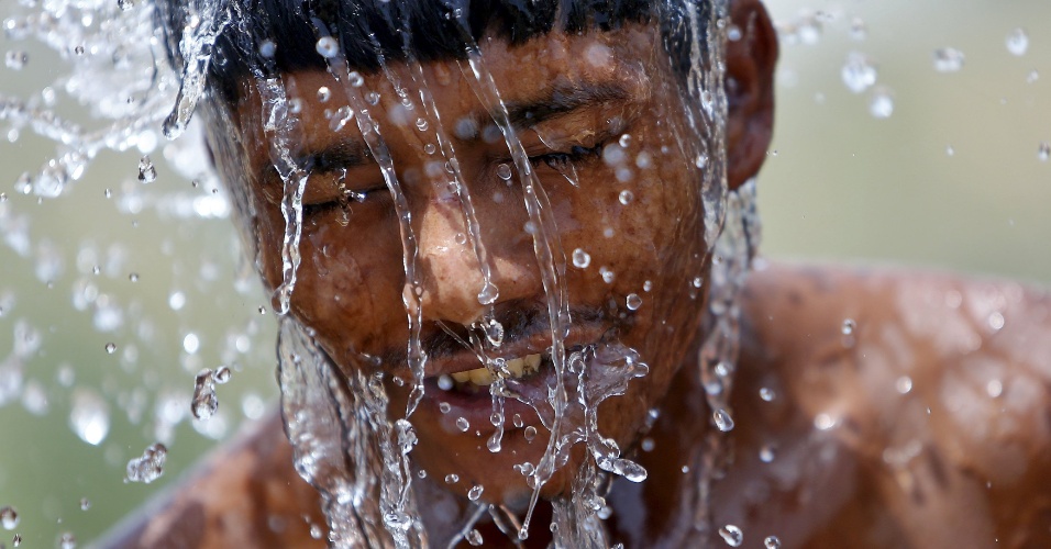 29.mai.2015 - Trabalhador se refresca em um dia quente de verão em Gurgaon, na Índia