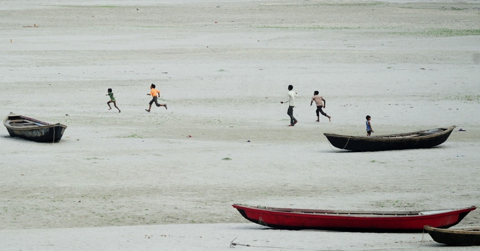 3.jun.2015 - Crianças tentam pegar pipas em uma área no leito seco do rio Ganga, em Allahabad, que caiu a um nível de água muito baixo devido ao calor extremo registrado na Índia