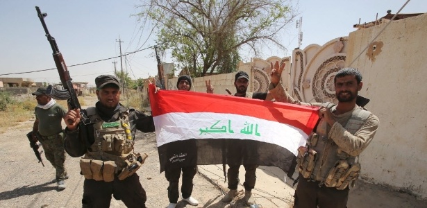 Combatentes xiitas iraquianos das unidades de Mobilização Popular seguram uma bandeira do Iraque na cidade de Baiji, ao norte de Tikrit, na província de Salahaddin. As Forças iraquianas avançaram contra o Estado Islâmico (EI) grupo jihadista e reconquistaram a cidade - Ahmad al-Rubaye/AFP