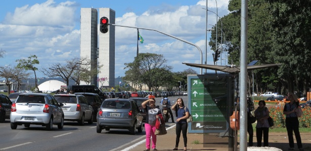 Passageiros esperam ônibus em parada na Esplanada dos Ministérios, em Brasília, com o prédio do Congresso Nacional ao fundo - Kleyton Amorim/UOL
