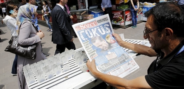 Vendedor lê jornal cuja manchete diz "queda" em referência a perda de poder do presidente turco Recep Tayyip Erdogan, em Ancara. O partido islamita conservador de Erdogan perdeu a maioria absoluta no Parlamento nas eleições de domingo e não poderá mais governar sozinho após 13 anos no poder  - Umit Bektas/Reuters