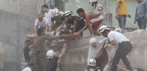 Bombeiros e civis ajudam no resgate de vítimas após explosão de prédio em Aleppo, no norte da Síria, em junho deste ano - Karam al-Masri/AFP