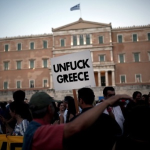Manifestante segura uma cartaz em alusão ao sentimento da população de que a Grécia está pagando um preço alto aos credores