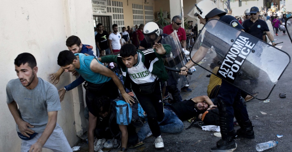 6.set.2015 - Policial bate em imigrantes durante protesto no porto de Lesbos, na Grécia. Eles pedem transferência imediata para Atenas. Mais de 230 mil refugiados e imigrantes chegaram à Grécia pelo mar este ano