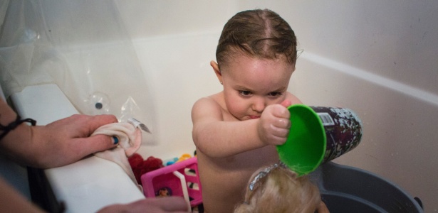 Menina brinca com boneca em banho improvisado com água de garrafa em Flint - Brittany Greeson/The New York Times