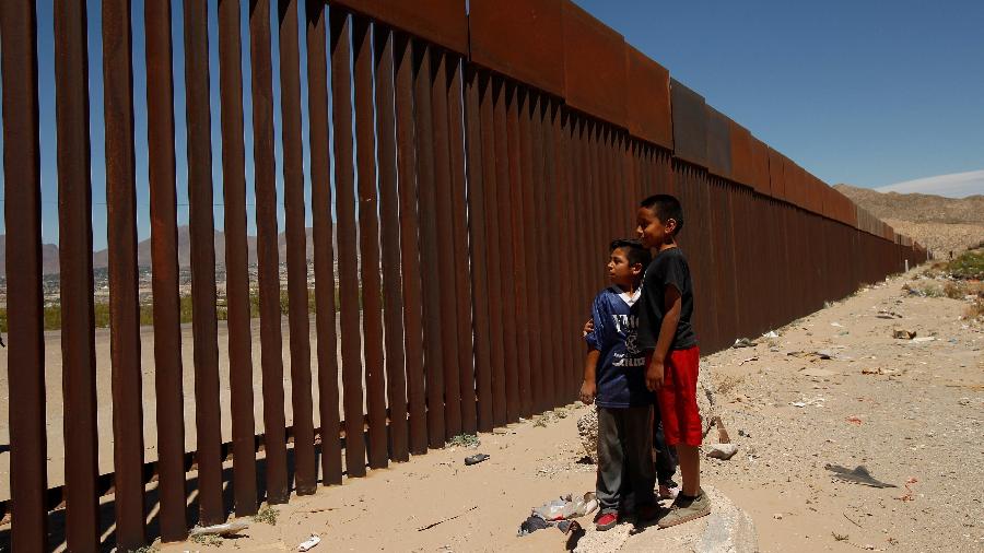 Crianças encaram o muro na fronteira entre os EUA e o México
