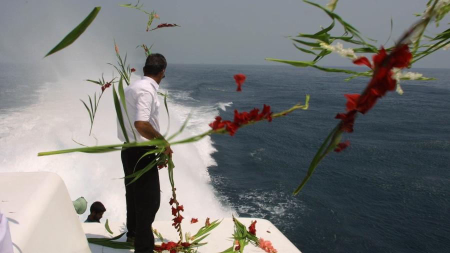 3.jul.01 - Parente de vítima iraniana de queda de avião derrubado pelos EUA em 1988 joga flores nas águas do Golfo Pérsico, local da tragédia  - Behrouz Mehri - 3.jul.01/AFP)