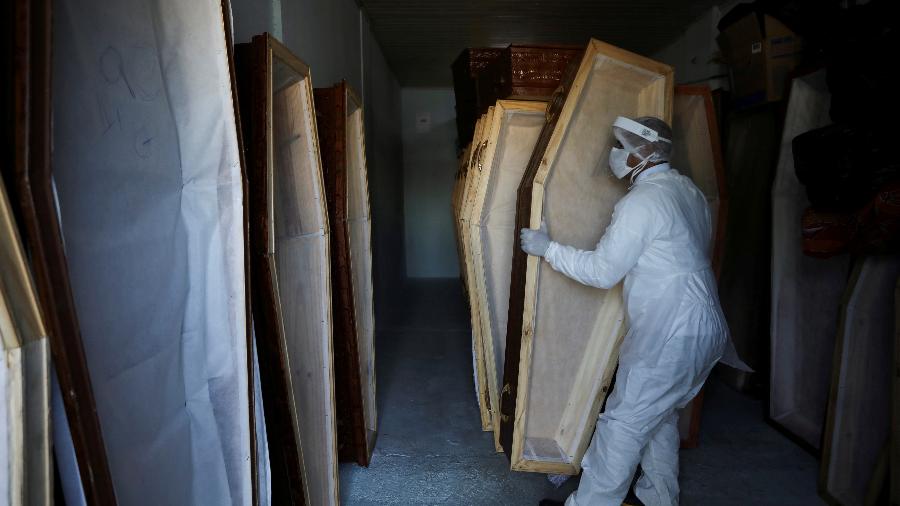 Um trabalhador, vestindo roupas de proteção, prepara caixões em meio ao surto de doença por coronavírus (COVID-19), em Manaus - BRUNO KELLY/REUTERS