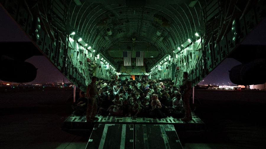 21.ago.2021 - Tripulação da Força Aérea dos EUA auxilia pessoas a bordo de aeronave em apoio à evacuação do Afeganistão no aeroporto de Cabul - Taylor Crul/Força Aérea dos EUA/ AFP