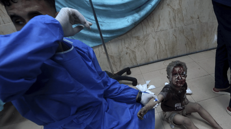 24.out.2023 - Médico cuida de criança ferida em um bombardeio de Israel na faixa de Gaza, no hospital Deir Al-Balah