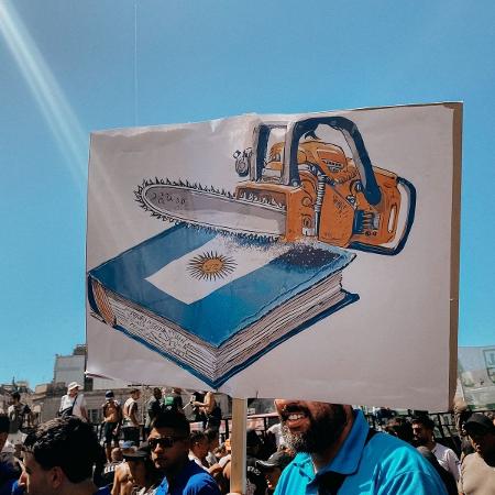 Cartaz de manifestante mostra a motosserra, símbolo da campanha de Milei à presidência