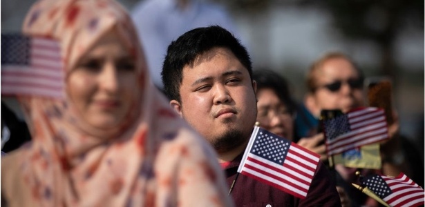 Novos cidadãos americanos agitam bandeiras do país durante cerimônia de naturalização - Getty Images