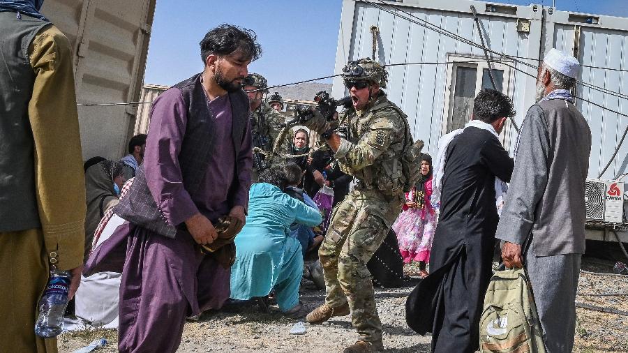 Soldado americano aponta arma para um passageiro afegão no aeroporto de Cabul, no Afeganistão - Wakil Kohsar/AFP