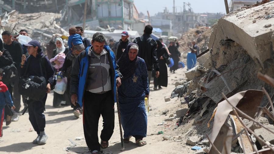 Palestinos caminham com seus pertences enquanto fogem de suas casas, após o exército israelense emitir ordens de evacuação, no bairro de Shujaiya, na Cidade de Gaza Palestinos caminham com seus pertences enquanto fogem de suas casas, após o exército israelense emitir ordens de evacuação, no bairro de Shujaiya, na Cidade de Gaza