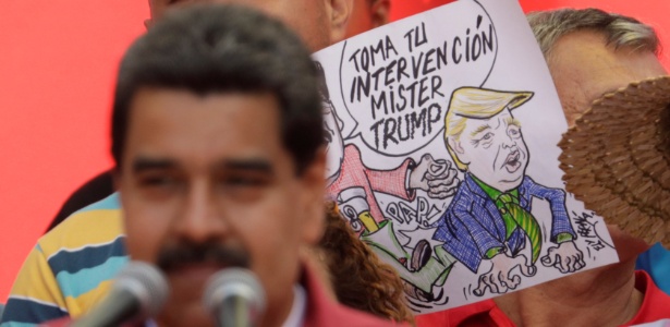 O presidente venezuelano Nicolás Maduro faz discurso com uma charge ao fundo onde se lê "toma a sua intervenção, Mr Trump´" - Ueslei Marcelino/ Reuters