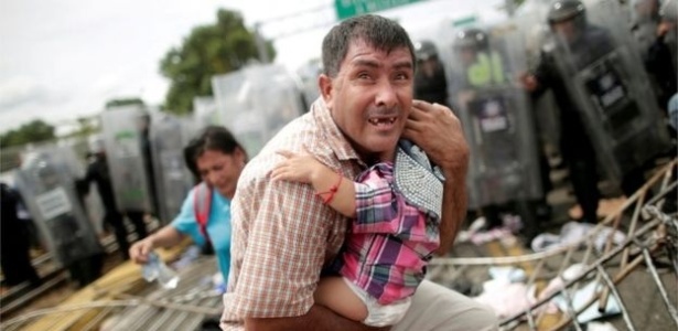 Hondurenho protege o filho após rompimento de grades na fronteira com a Guatemala - Reuters