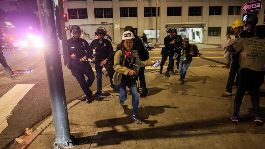 Profissional da imprensa correndo de policiais durante operação de toque de recolher Profissional da imprensa correndo de policiais durante operação de toque de recolher