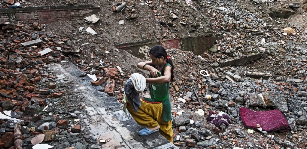 Nepalesa carrega água no que restou de seu bairro, em Katmandu, dois meses após o terremoto - Narendra Shrestha/Efe