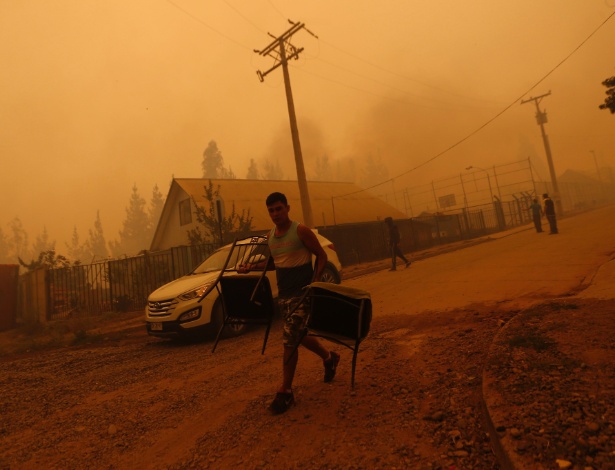 26.jan.2017 - Homem carrega cadeiras em San Ramon após incêndio florestal devastar a vizinha Santa Olga, no Chile - Pablo Vera Lisperguer/AFP