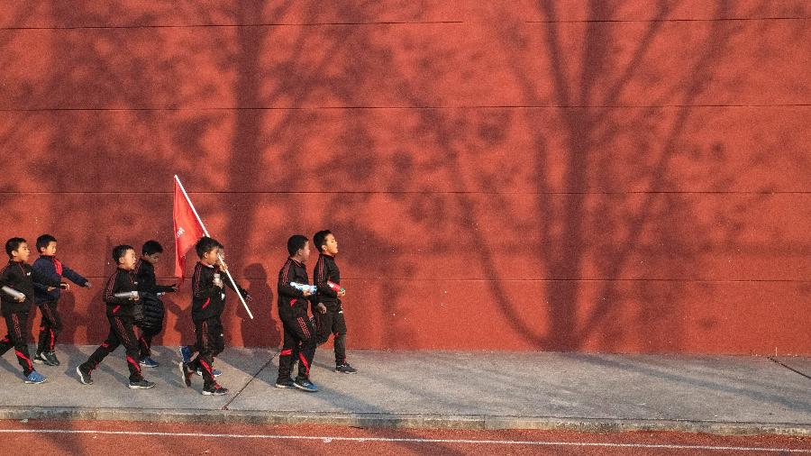 Estudantes do Clube dos Meninos de Verdade cantam enquanto caminham para o ônibus no final do treinamento em Pequim - Gilles Sabrié/The New York Times