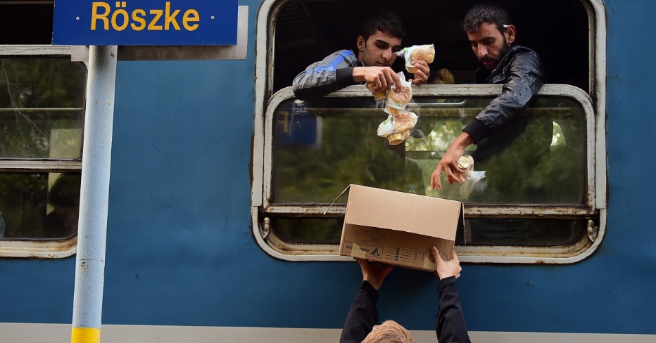 15.set.2015 - Refugiados recebem sanduíches de café da manhã na estação ferroviária Röszke, na Hungria, região que faz fronteira com a Sérvia e onde o governo construiu um muro para evitar a entrada de mais imigrantes
