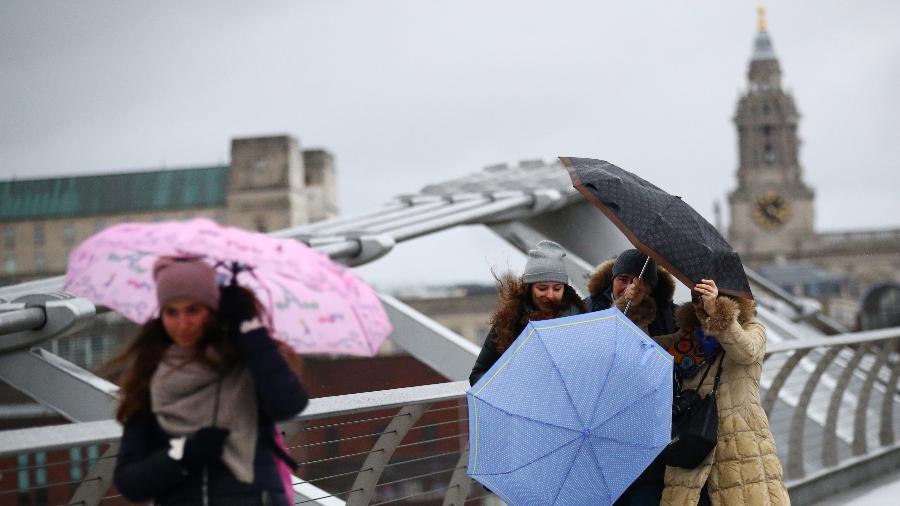 Pessoas lutam para segurar seus guarda-chuvas abertos durante a tempestade Dennis, em Londres  - Hannah McKay/Reuters