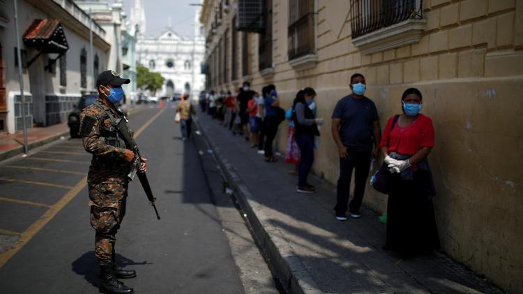 Soldado vigia pessoas esperando em uma fila de banco a uma distância segura durante quarentena em Santa Ana, El Salvador - JOSE CABEZAS/REUTERS - JOSE CABEZAS/REUTERS