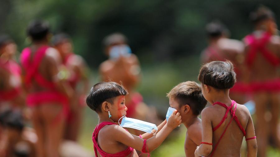 Menino da etnia ianomâmi coloca máscara em outra criança em Alto Alegre, Roraima - ADRIANO MACHADO