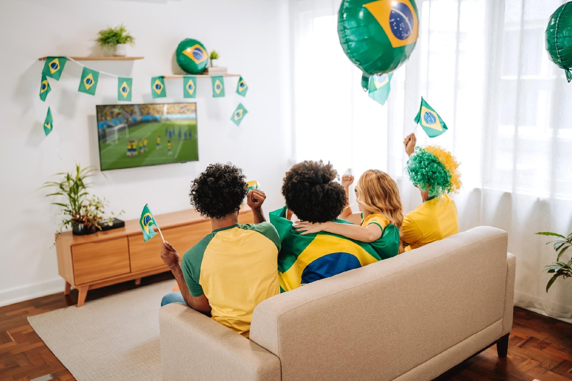 Amigos assistem à jogo de futebol do Brasil em TV numa sala - undefined