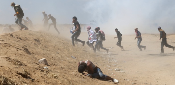 15.mai.2018 - Palestinos correm de bombas de gás lacrimogênio durante confronto com forças israelenses na Faixa de Gaza - Ibraheem Abu Mustafa/Reuters