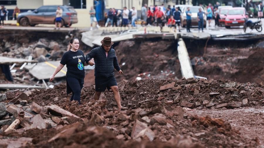 ALBUM_Pessoas atravessam estrada destruída pelas enchentes em Roca Sales, no Rio Grande do Sul